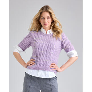 Frau in einem lila Pullover mit kurzen Ärmeln, steht selbstbewusst mit verschränkten Händen.
