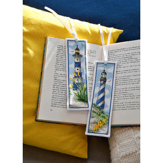 Zwei Lesezeichen mit Leuchttürmen auf einem offenen Buch.