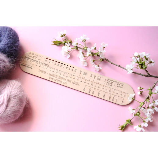 Sockenlineal für 6-fach Garne auf einem rosa Hintergrund mit Wolle.