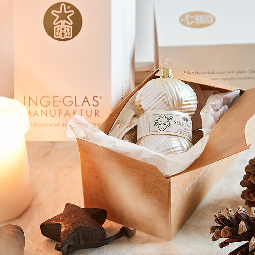 Weihnachtskugel in Form eines Wollknäuels, beige, in Geschenkbox auf einem Tisch.