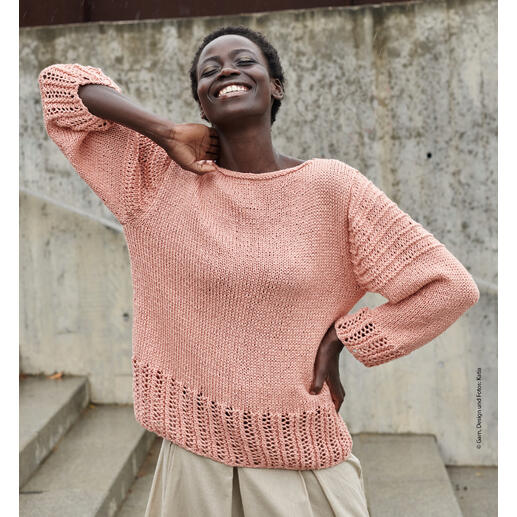 Frau in rosafarbenem Pullover mit lässigem Look, lächelt in urbaner Umgebung