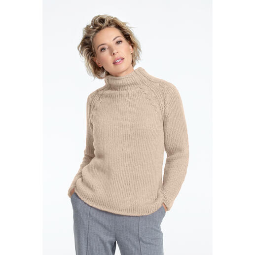Frau in beigefarbenem Pullover aus NewWool, posiert nachdenklich.