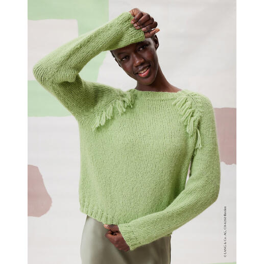 Frau in einem grünen Top-Down-Pullover aus Malou Light mit Fransen.