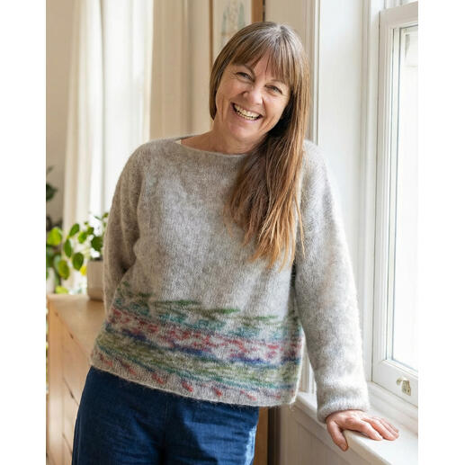 Pullover aus Wonder Sweater mit buntem Muster, lächelnde Frau im Raum.