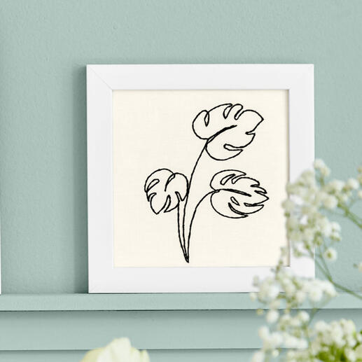 Stickbild mit stilisierten Pflanzenmotiven in einem weißen Rahmen.