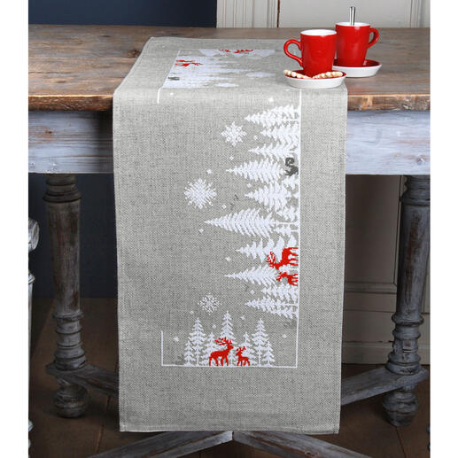 Tischläufer mit Wintermotiven, darunter Rehe und verschneite Tannenbäume.