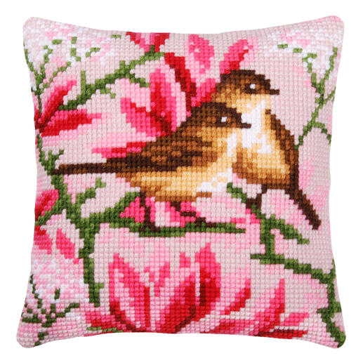 Kissen mit Magnolienblüten und Vögeln auf rosa Hintergrund.