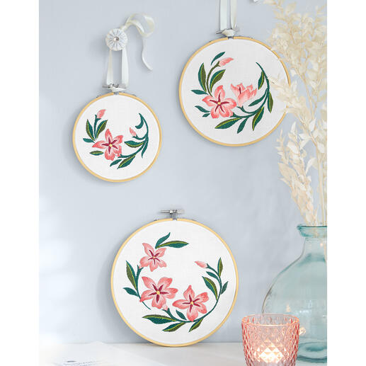 Drei runde Stickereien mit Oleanderblüten an einer Wand