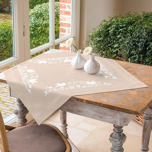 Tischdecke mit weißen Vogelmotiven auf beigefarbenem Hintergrund