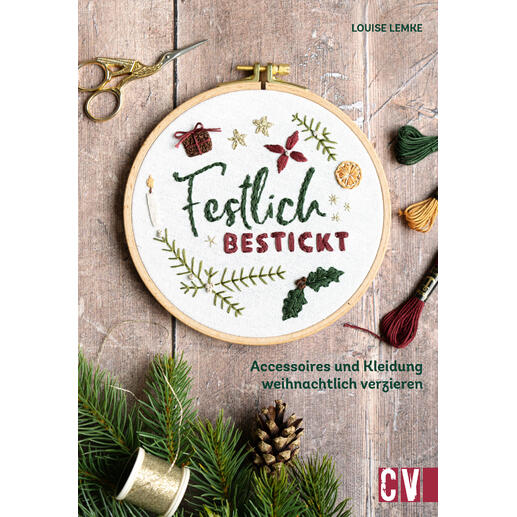 Buch über festliche Stickereien mit weihnachtlichen Motiven auf einem Tisch.
