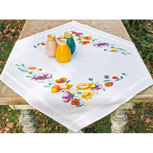 Tischwäsche mit Mohnblumen und bunten Vasen auf dem Tisch.