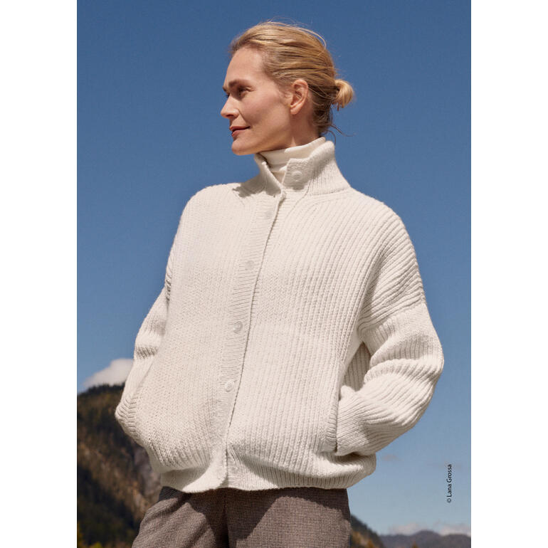 Frau trägt einen weißen Cardigan aus Alta Moda Alpaca von Lana Grossa unter blauem Himmel.