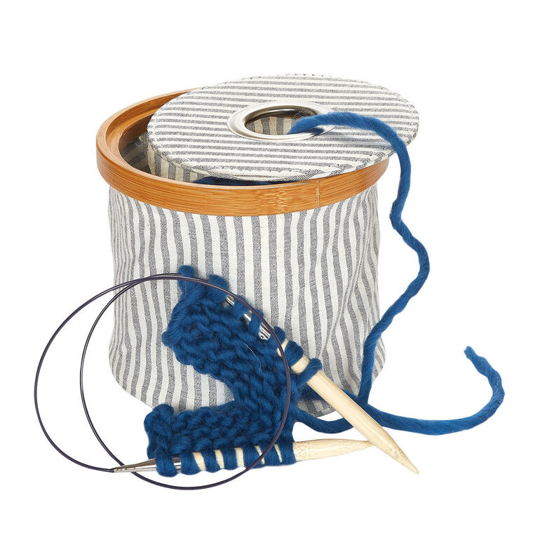 Holzwollspender mit grauer Wickelung und Stricknadeln.