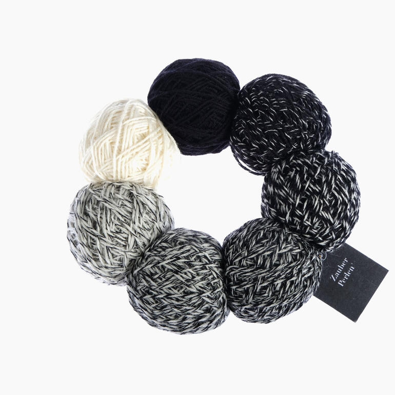 Acht Zauberperlen® in Schwarz, Weiß und Grau auf einer schwarzen Fläche angeordnet.