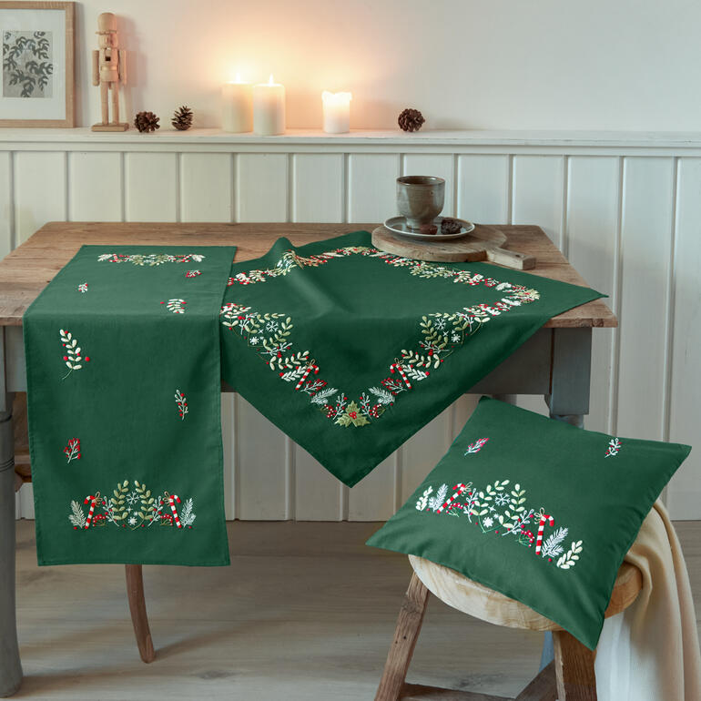 Ensemble 'Winterfreude' in Grün mit dekorativen Elementen auf Tisch und Kissen.