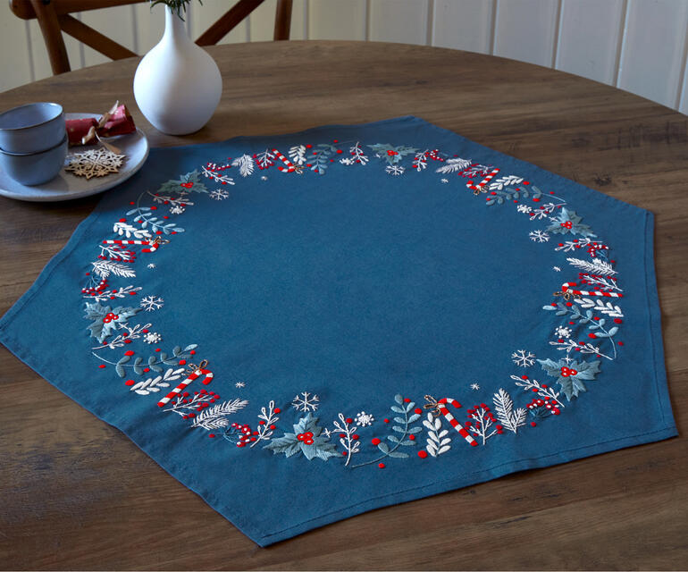 Hexagonale Tischdecke in Blau mit rot-weißer Winterbordüre.