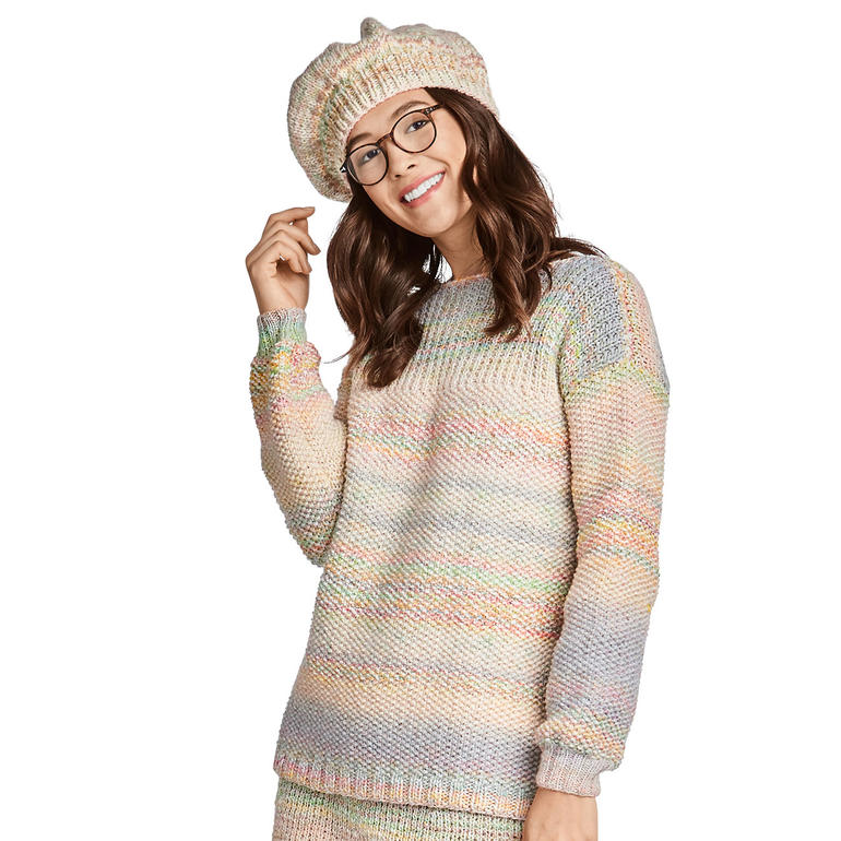 Bunter Pullover in Pastelltönen, lässig getragen mit einer Mütze, vor hellem Hintergrund.