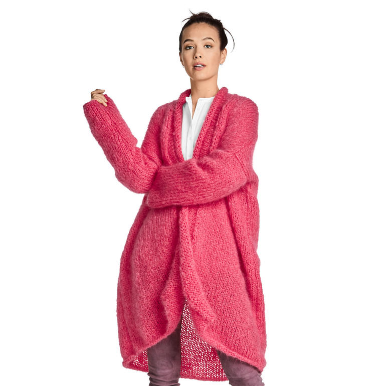 Frau in langem, pinken Mantel aus Feelana, mit verschränkten Armen.