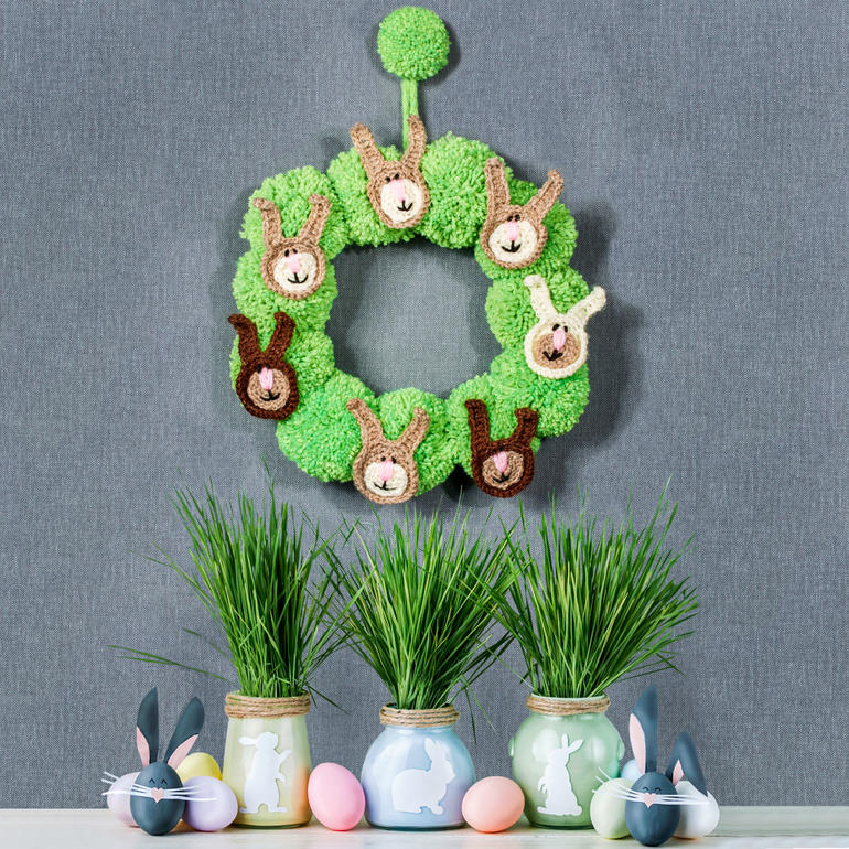Grüner Kranz mit Hasenköpfen und Ostereiern als Dekoration.