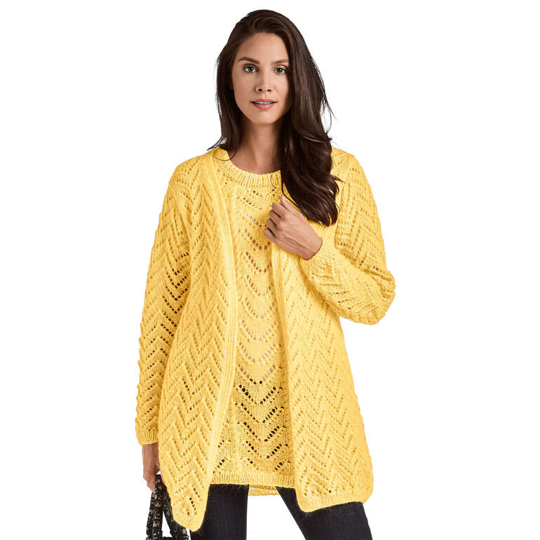 Frau in gelber Strickjacke und T-Shirt, lächelt in die Kamera vor einem weißen Hintergrund.