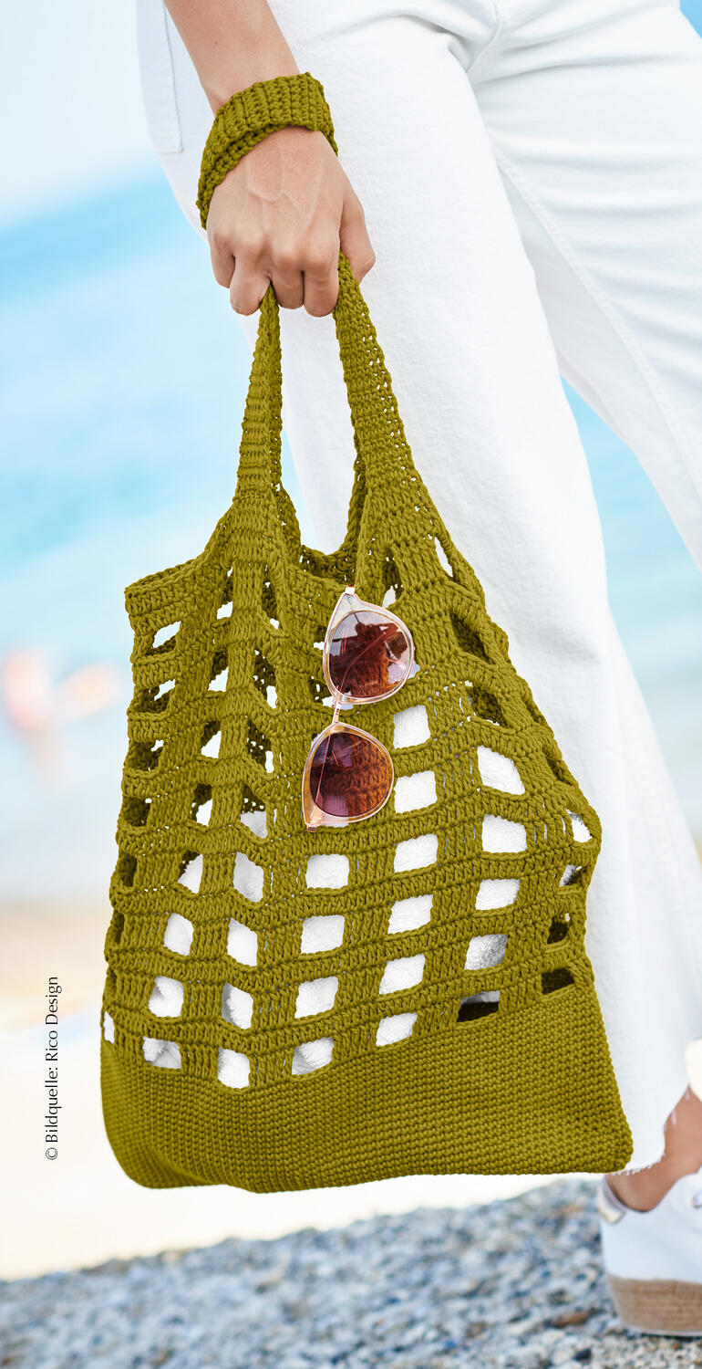 Olivenfarbene Tasche aus Bio-Baumwolle mit Sonnenbrille in der Hand.