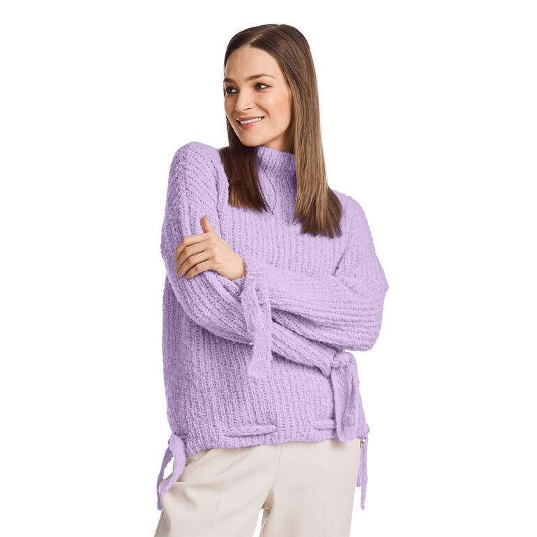 Frau trägt lila Pullover mit Bändern an den Ärmeln und lockerer Passform.
