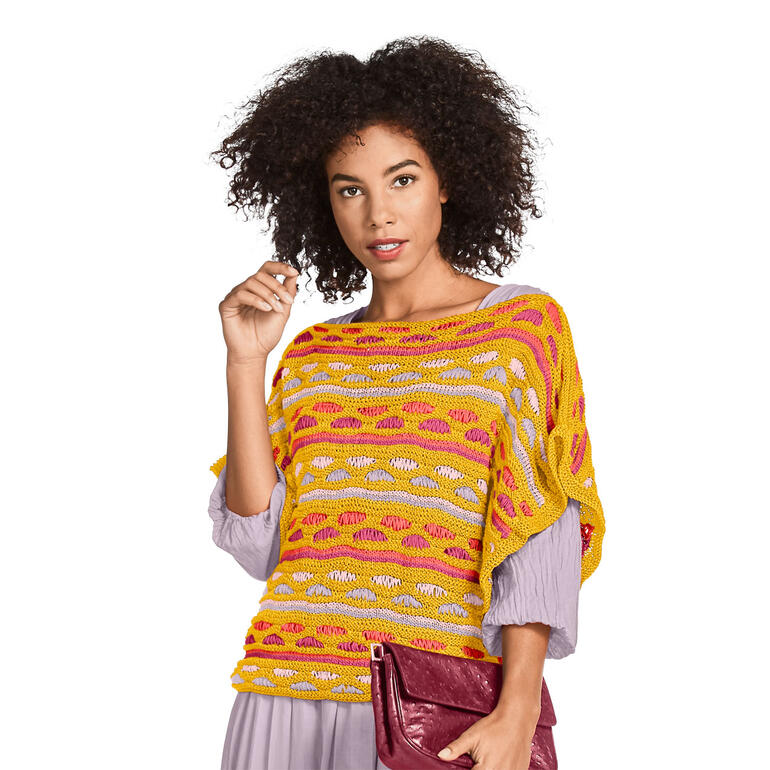 Frau in einem bunten Damenpullover aus Cottonprima, posiert vor neutralem Hintergrund.
