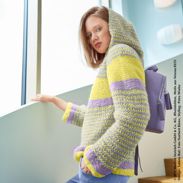 Frau in einem hellen Hoodie mit Kapuze aus Aerea, mit lässigem Rucksack.