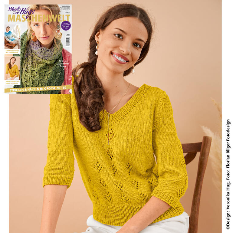 Frau trägt einen lockeren Pullover aus Merino Stretch in Gelb, lächelnd in die Kamera.