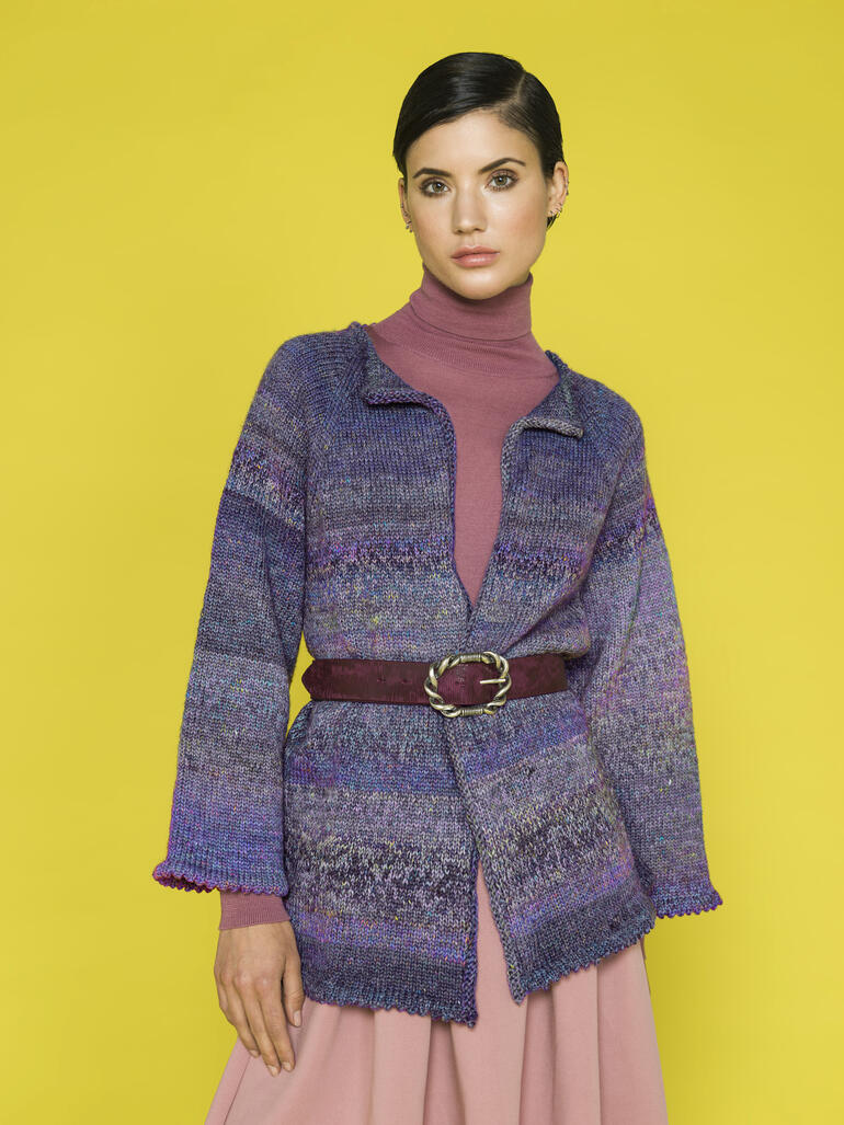 Frau in bunter Jacke mit Gürtel vor einem leuchtend gelben Hintergrund