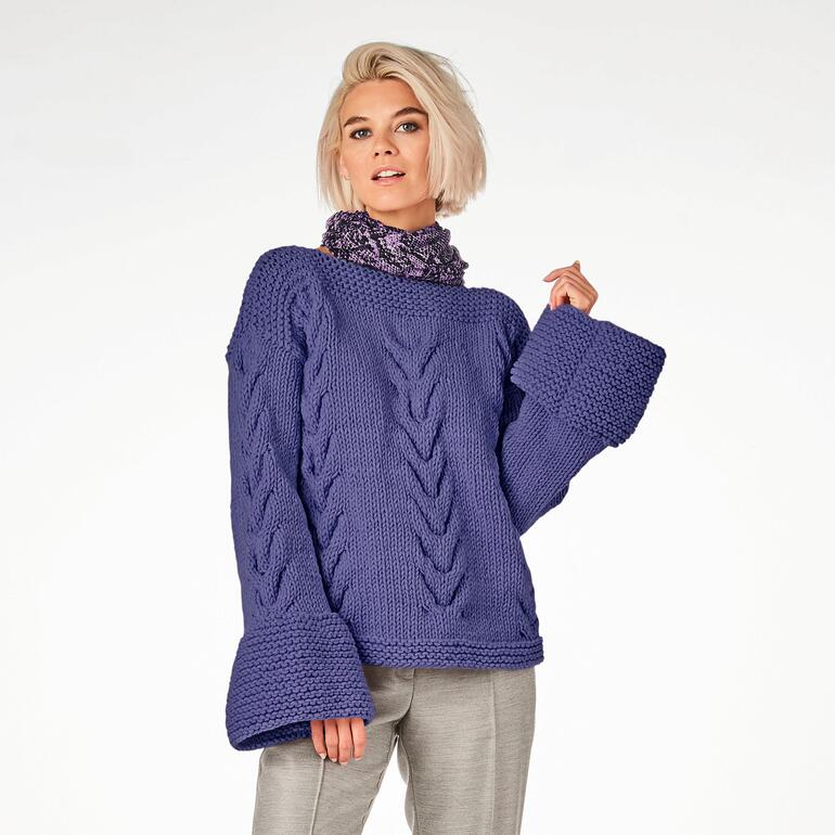 Lila Pullover aus Merino Dick, getragen von einer Frau mit kurzem, hellem Haar.