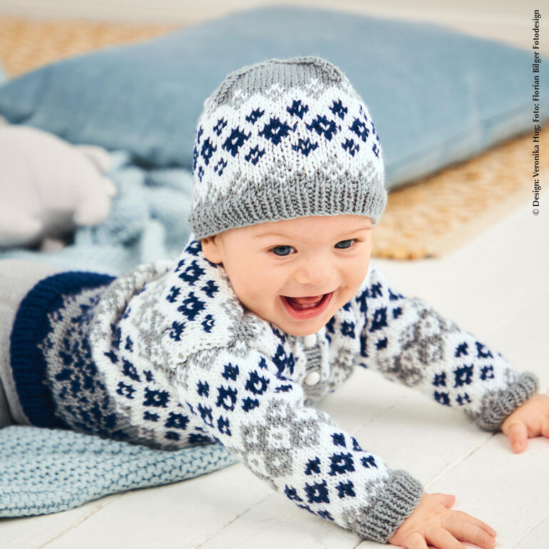 Babyjacke und Mütze aus Charity, lachendes Baby auf dem Boden.
