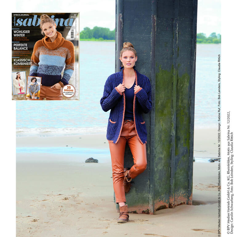 Frau trägt eine marineblaue Jacke aus Frigga mit kontrastierenden Taschen, am Wasser.