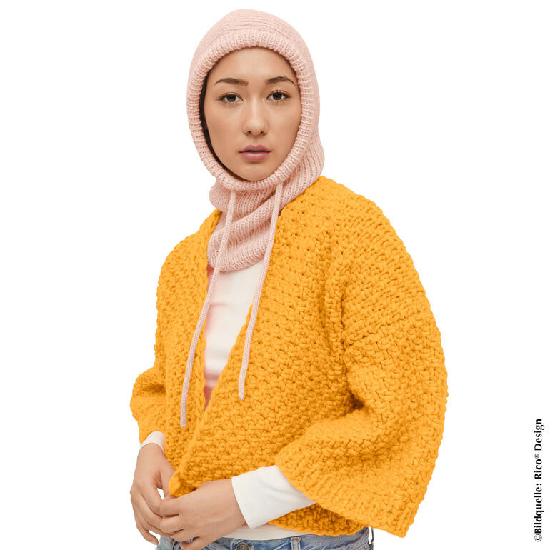 Frau trägt eine zweifarbige Balaclava aus Baby Alpaca, in einer orangenen Jacke.