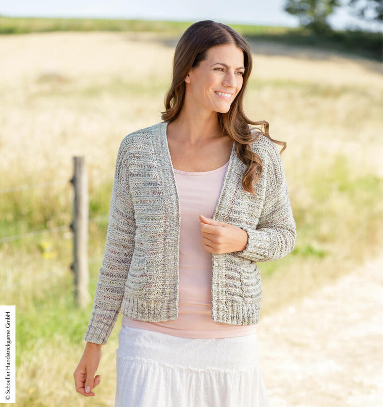 Helle Jacke aus Playa Organic Cotton, Frau steht lächelnd vor einem ländlichen Hintergrund.