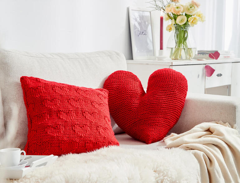 Kissenhülle aus Enny, auf einem Sofa mit einem weiteren Kissen und einer Tasse abgebildet.