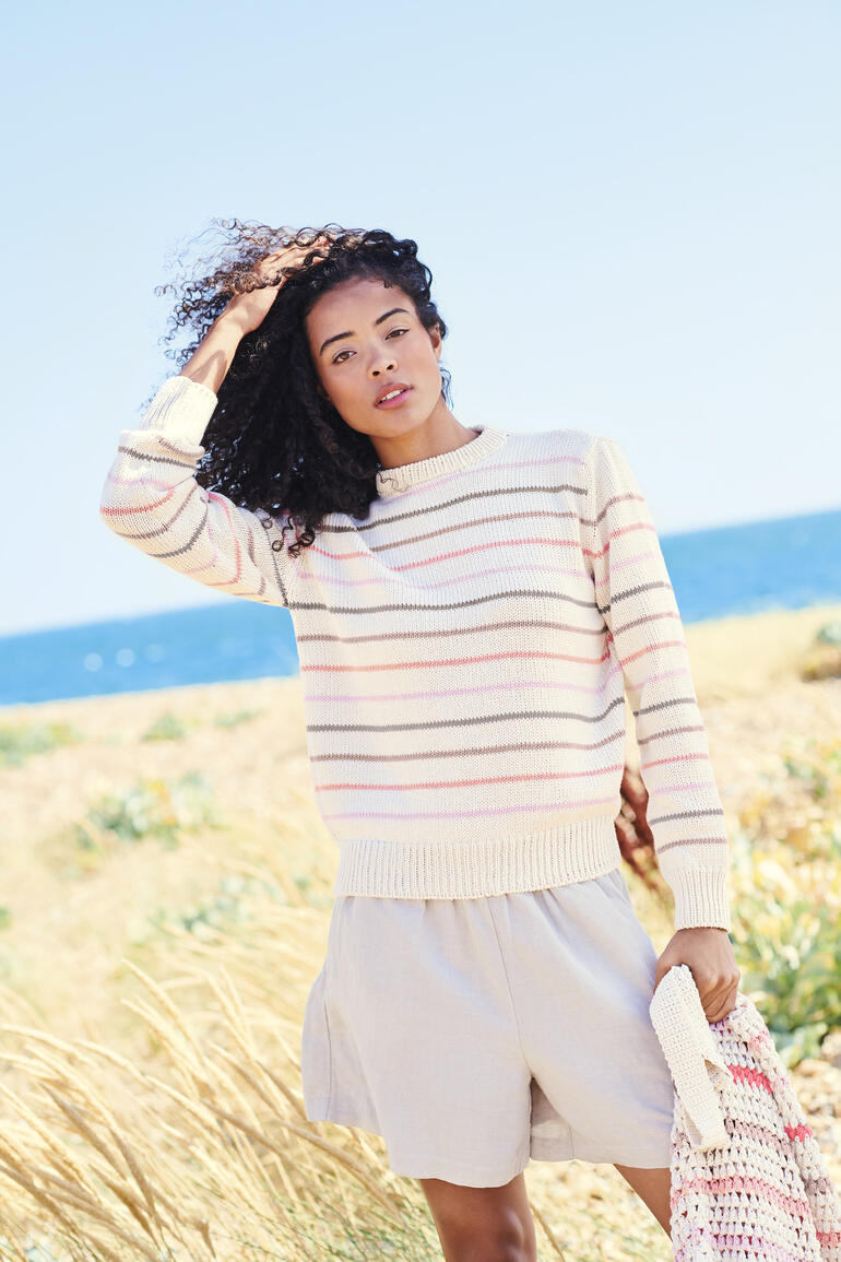 Beige gestreifter Pullover mit Rundhalsausschnitt am Strand.