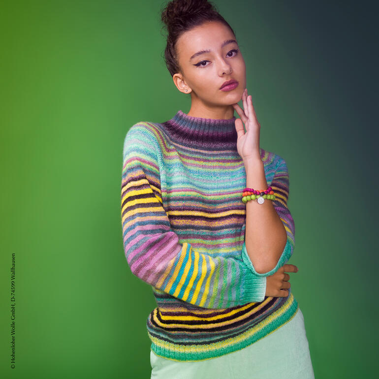 Frau trägt einen gestreiften Pullover aus Zauberball® von Schoppel Wolle in einem sanften Licht.