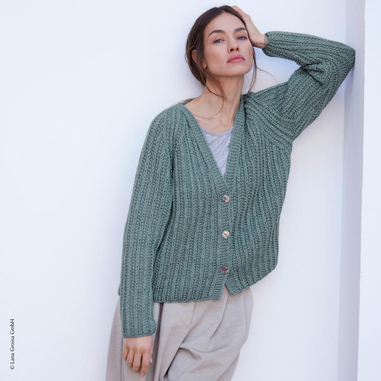 Jacke aus New Classic in sanften Grüntönen, lässig über die Schulter getragen.