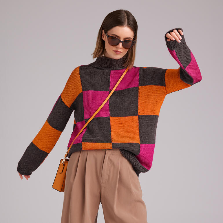 Frau präsentiert einen bunten Pullover aus Merinowolle