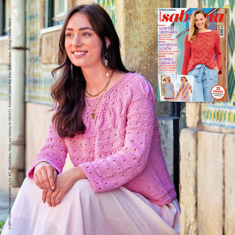 Frau sitzt in einem Mustermix-Pullover aus Recycle & Cotone vor einem Magazin.