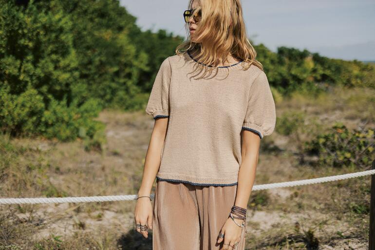 Frau trägt beigen Pulli mit kurzen Ärmeln aus Mandarin Petit in der Natur.