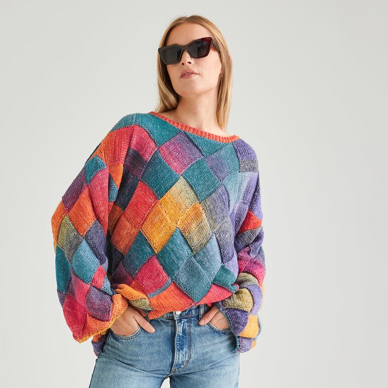 Frau in buntem Oversize-Pulli posiert in stylischer Sonnenbrille.