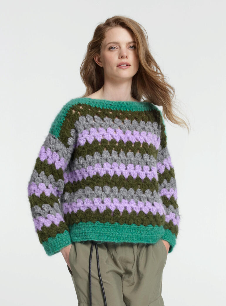 Häkelpullover aus Nappy in Grün, Grau und Lila, getragen von einer Frau.