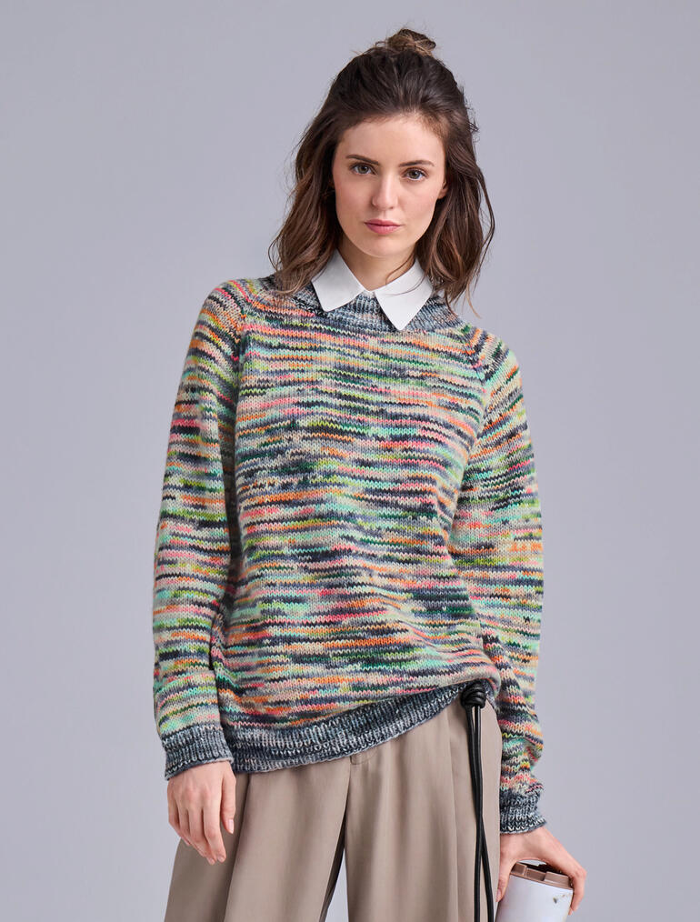 Pullover aus Merino-Print in bunten Streifen, getragen von einer Frau mit Hemd.