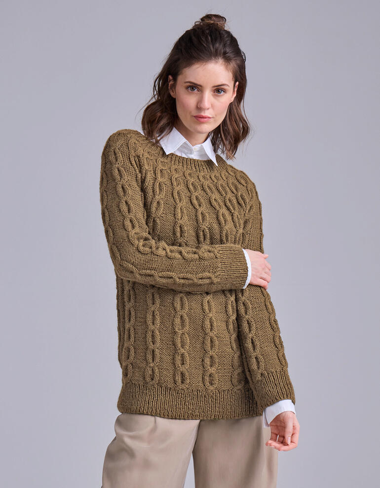 Olivenfarbener Pullover mit Zopfmuster vor grauem Hintergrund.