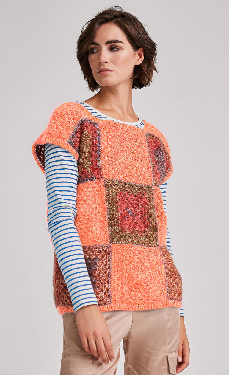 Orange-farbener Pullunder mit bunten, gemusterten Ärmeln.