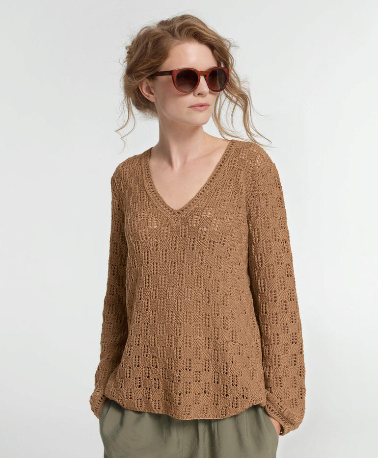 Frau in braunem Pullover mit V-Ausschnitt trägt Sonnenbrille.