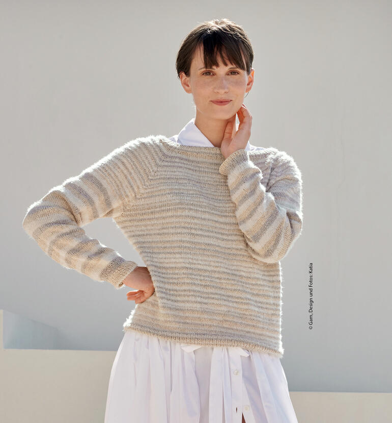 Frau trägt beigen Pullover aus Lua, schaut nachdenklich mit kurzem, gepolstertem Stil.