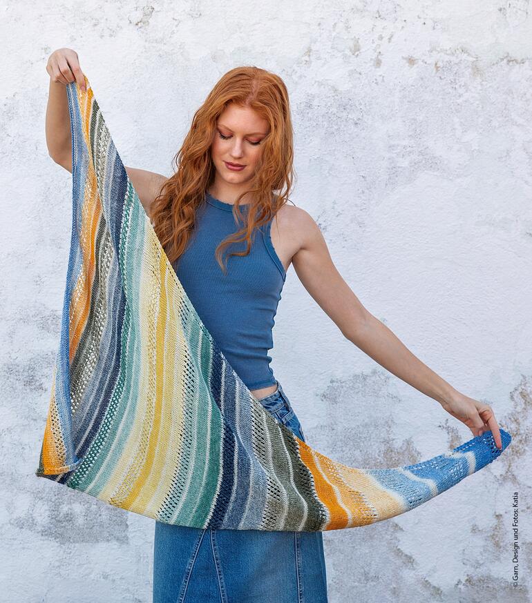 Frau zeigt ein mehrfarbiges Schultertuch, es ist über die Schulter geworfen.